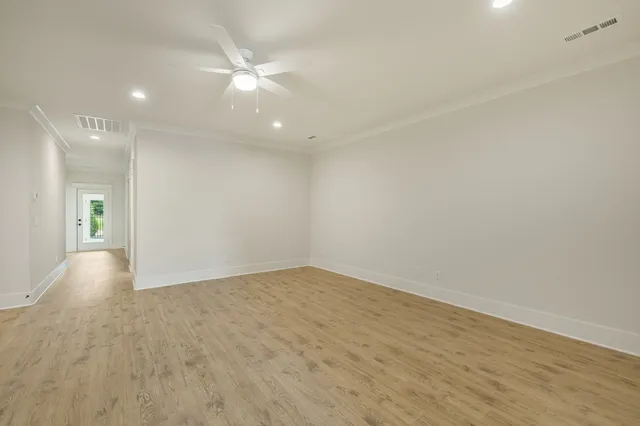 an empty room with wooden floor and fan