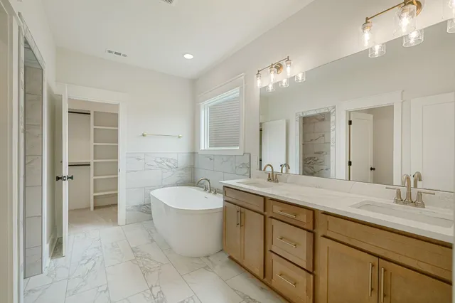 a spacious bathroom with a double vanity sink mirror and bathtub