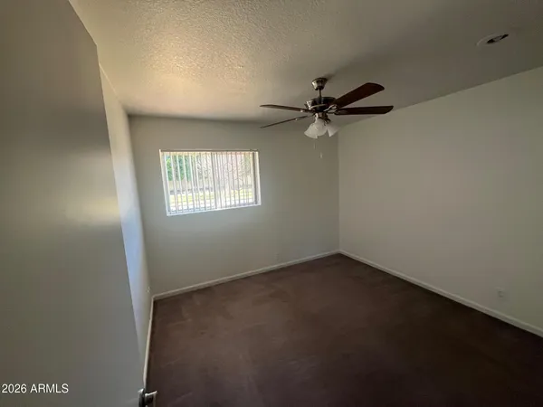 an empty room with a window and a fan