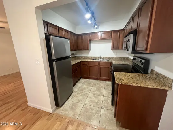 a kitchen with granite countertop wooden cabinets stainless steel appliances and a counter space