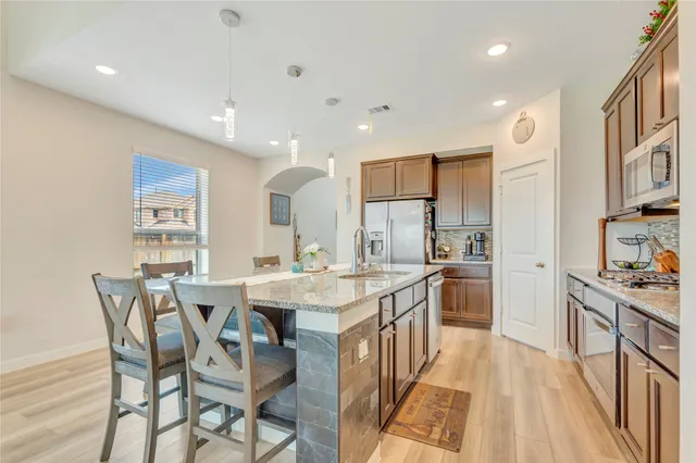 a kitchen with stainless steel appliances kitchen island granite countertop a table chairs sink and cabinets