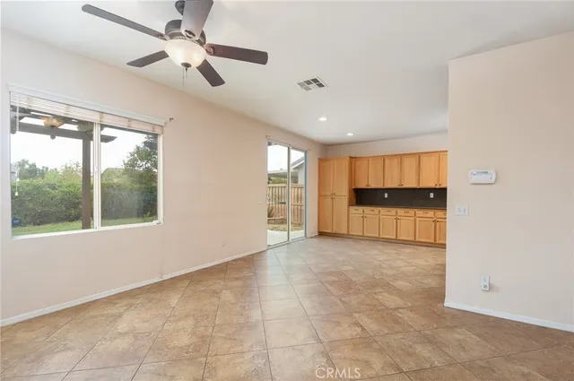 a view of an empty room with a window and kitchen view