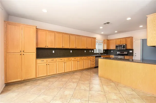 a large kitchen with stainless steel appliances granite countertop a stove a sink and a refrigerator