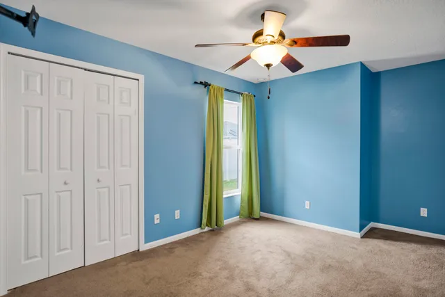 an empty room with closet and a chandelier fan