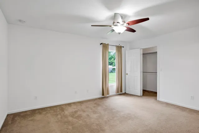 an empty room with a ceiling fan and a window