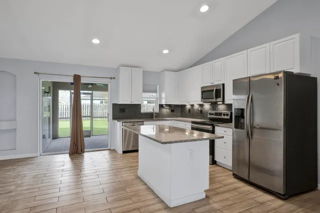 a kitchen with a refrigerator a sink dishwasher and a stove with wooden floor