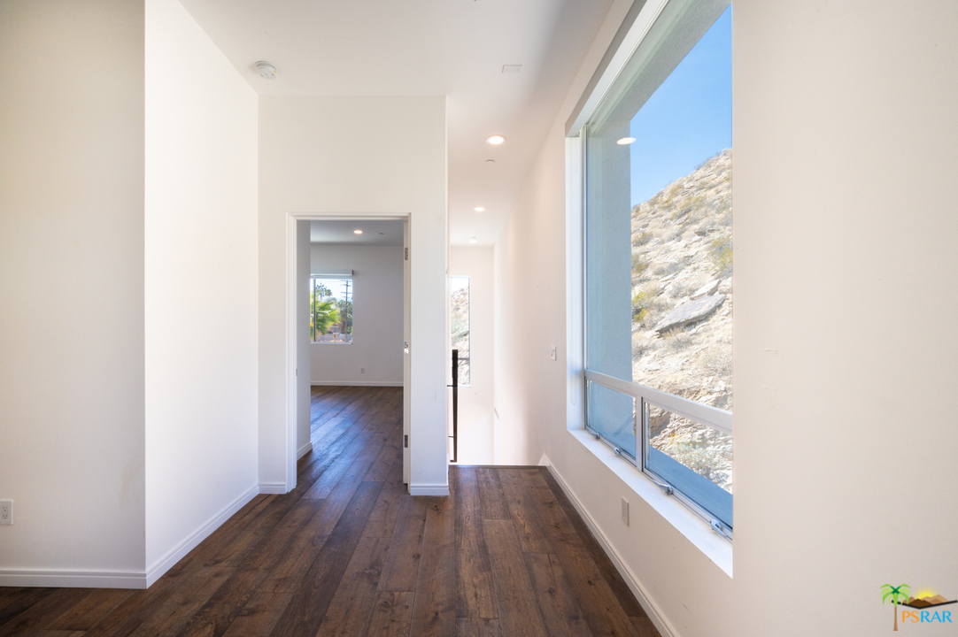 1521 South Belardo Road Palm Springs, CA 92264 - Photo 31 of 37 a view of a hallway with wooden floor and windows with curtains