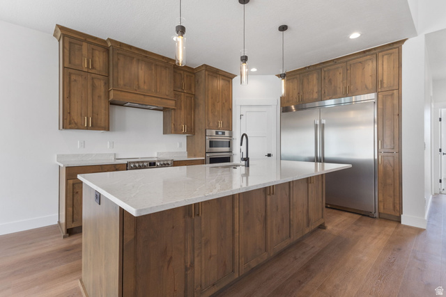 638 East Mountain Road North Ogden, UT 84414 - Photo 5 of 28 Kitchen featuring stainless steel appliances, pendant lighting, light stone countertops, an island with sink, and light wood finished floors