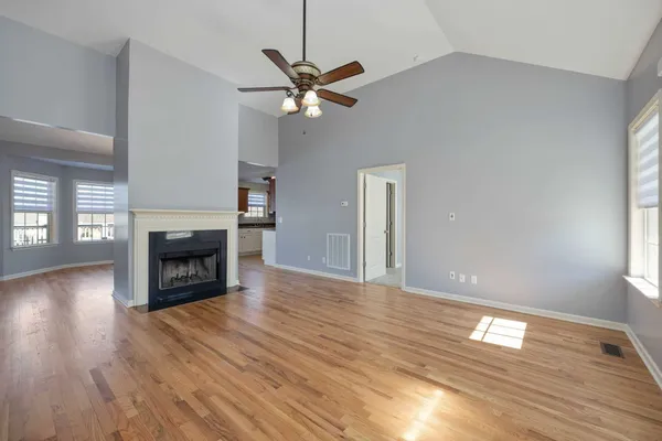 a view of an empty room with wooden floor fireplace and a window