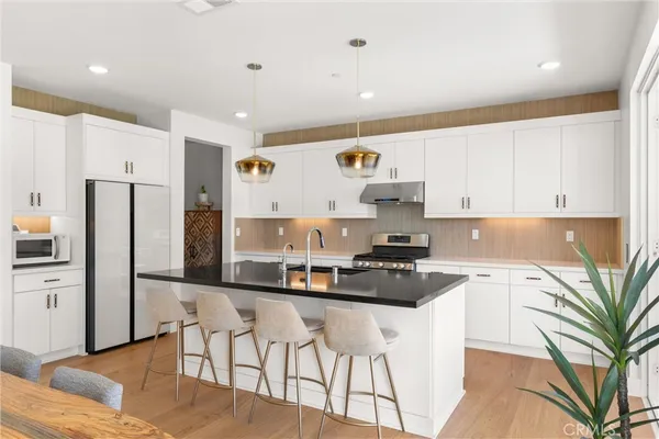 a kitchen with stainless steel appliances granite countertop a stove top oven a sink a dining table and chairs with wooden floor