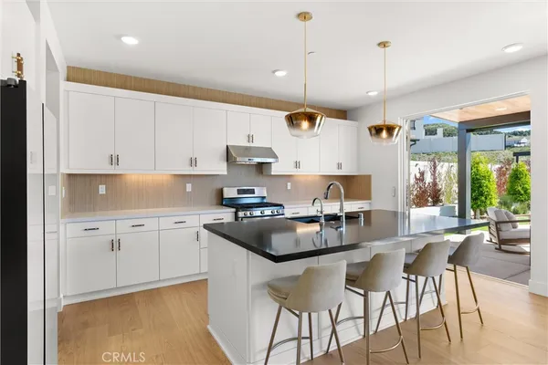 a kitchen with stainless steel appliances granite countertop a stove and a view of living room