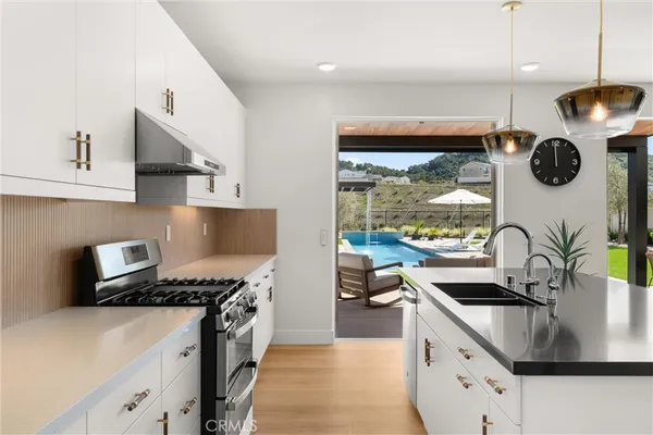 a kitchen with stainless steel appliances granite countertop a sink a stove and a refrigerator