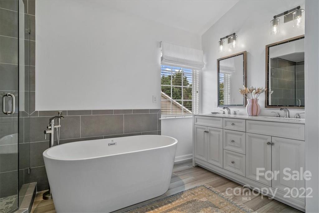 244 Sand Paver Way, Unit 60 Fort Mill, SC 29708 - Photo 24 of 42 a bathroom with a bathtub a double vanity sink a window and a mirror
