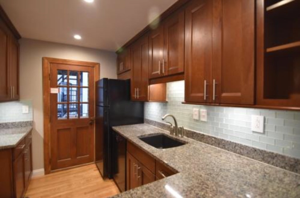 84 Gordon Street, Unit 206 Boston, MA 02135 - Photo 6 of 15 a kitchen with granite countertop stainless steel appliances wooden cabinets a sink and a refrigerator