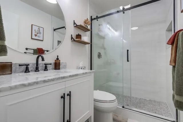 a bathroom with a granite countertop sink a toilet and shower