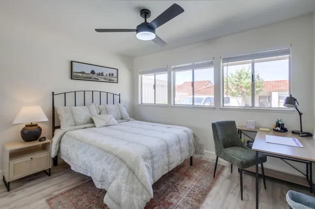 a bedroom with a bed a chair and a large window