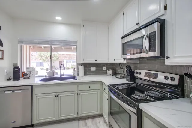 a kitchen with white cabinets appliances and a window