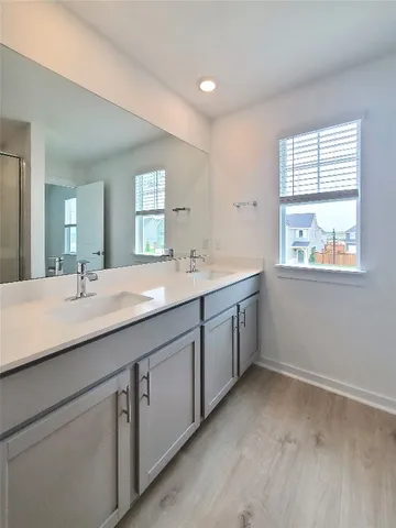a bathroom with double sink large mirror and a window
