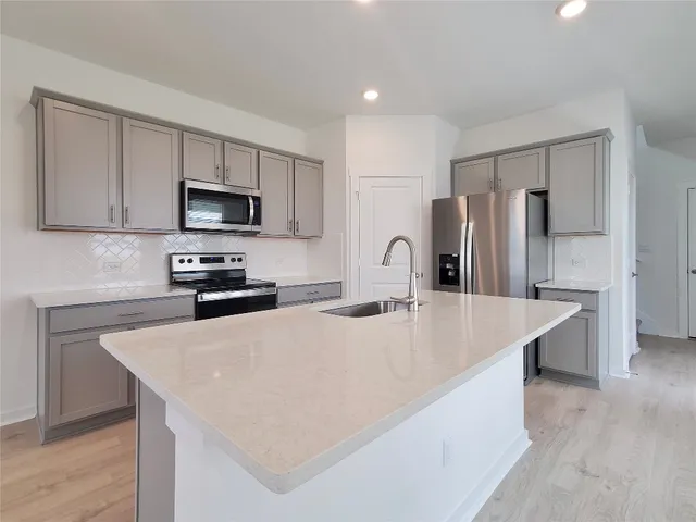 a kitchen with stainless steel appliances a refrigerator microwave stove sink and cabinets