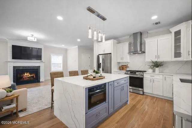 a kitchen with stainless steel appliances granite countertop a stove top oven a sink dishwasher and a fireplace with wooden floor