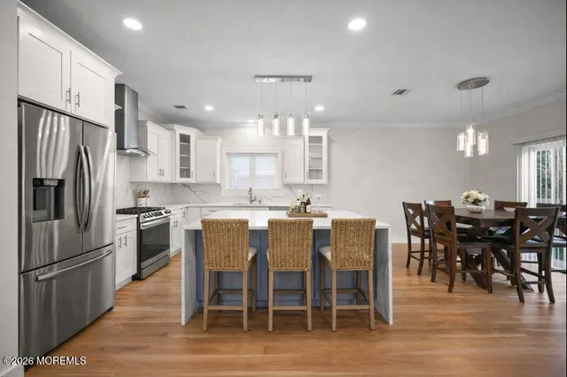 a kitchen with stainless steel appliances granite countertop a dining table chairs refrigerator and sink