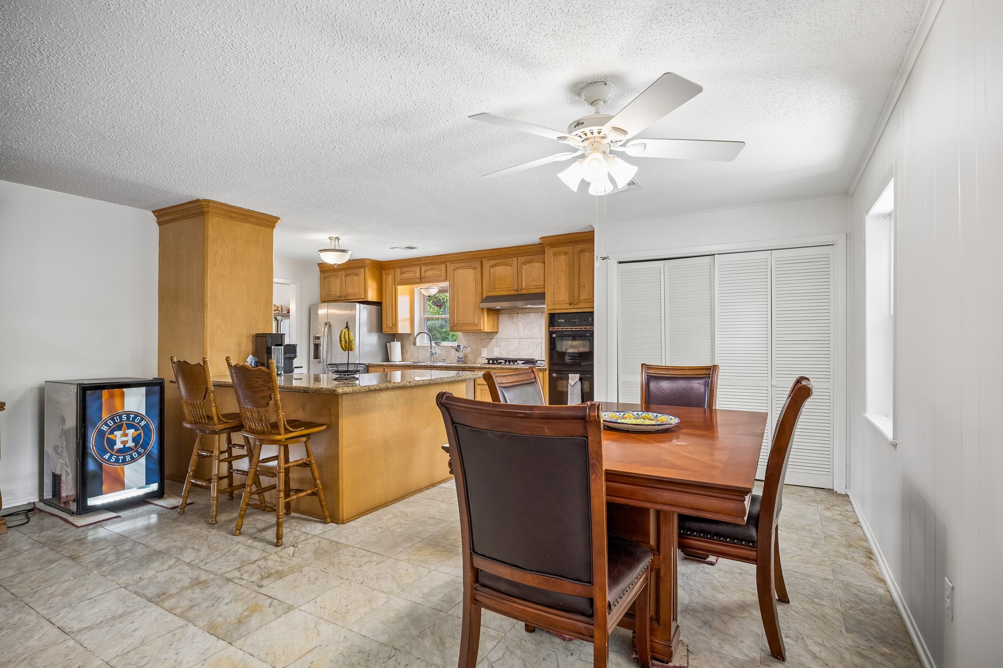 413 Mebane Lane Rosenberg, TX 77471 - Photo 17 of 30 This photo features a cozy kitchen and dining area with warm wood cabinetry, a large island with bar seating. The space is bright with ample room for dining and entertaining.
