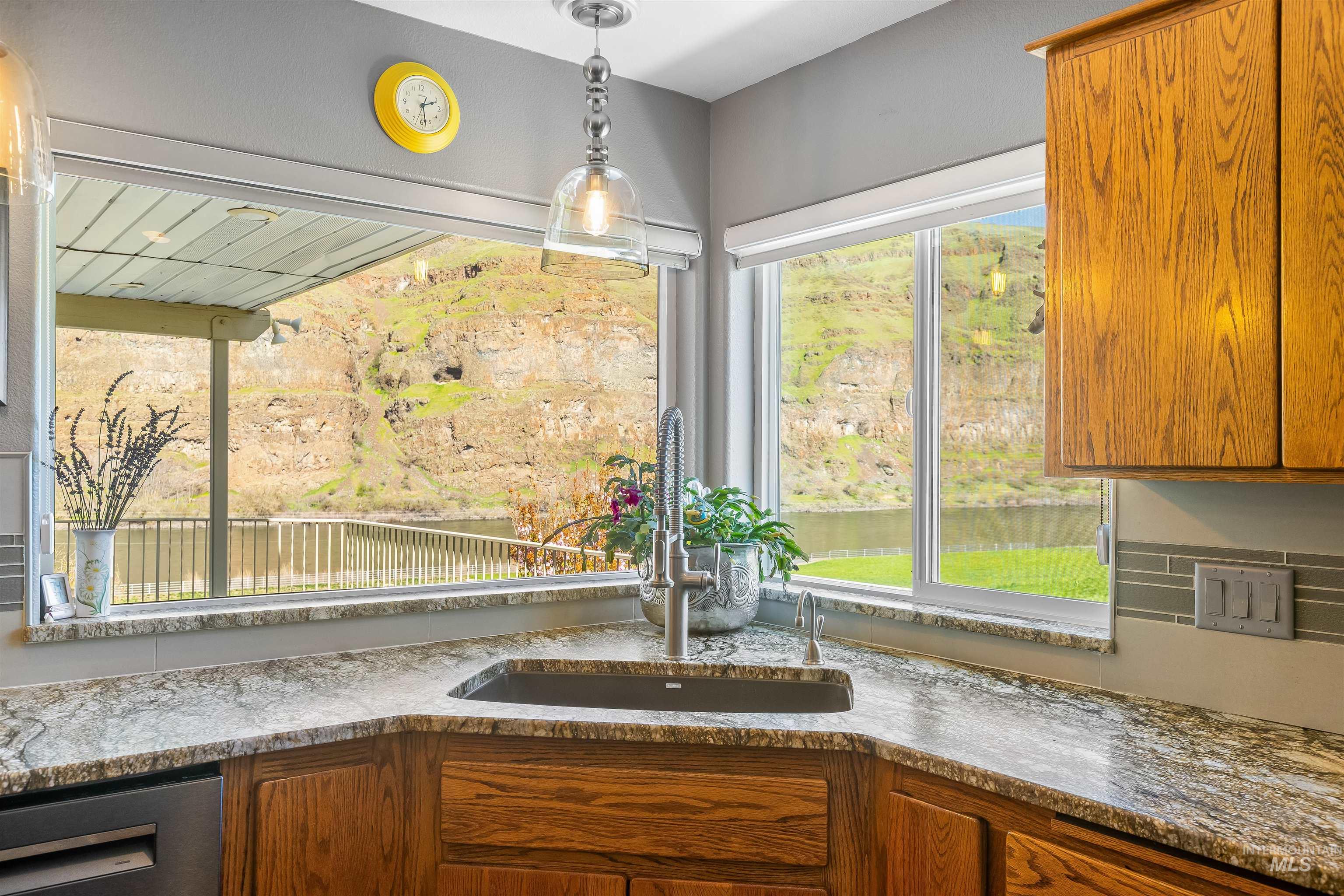 11056 Snake River Road Asotin, WA 99402 - Photo 17 of 50 Kitchen with wood finish cabinetry, dark stone counters, stainless steel dishwasher, and decorative light fixtures