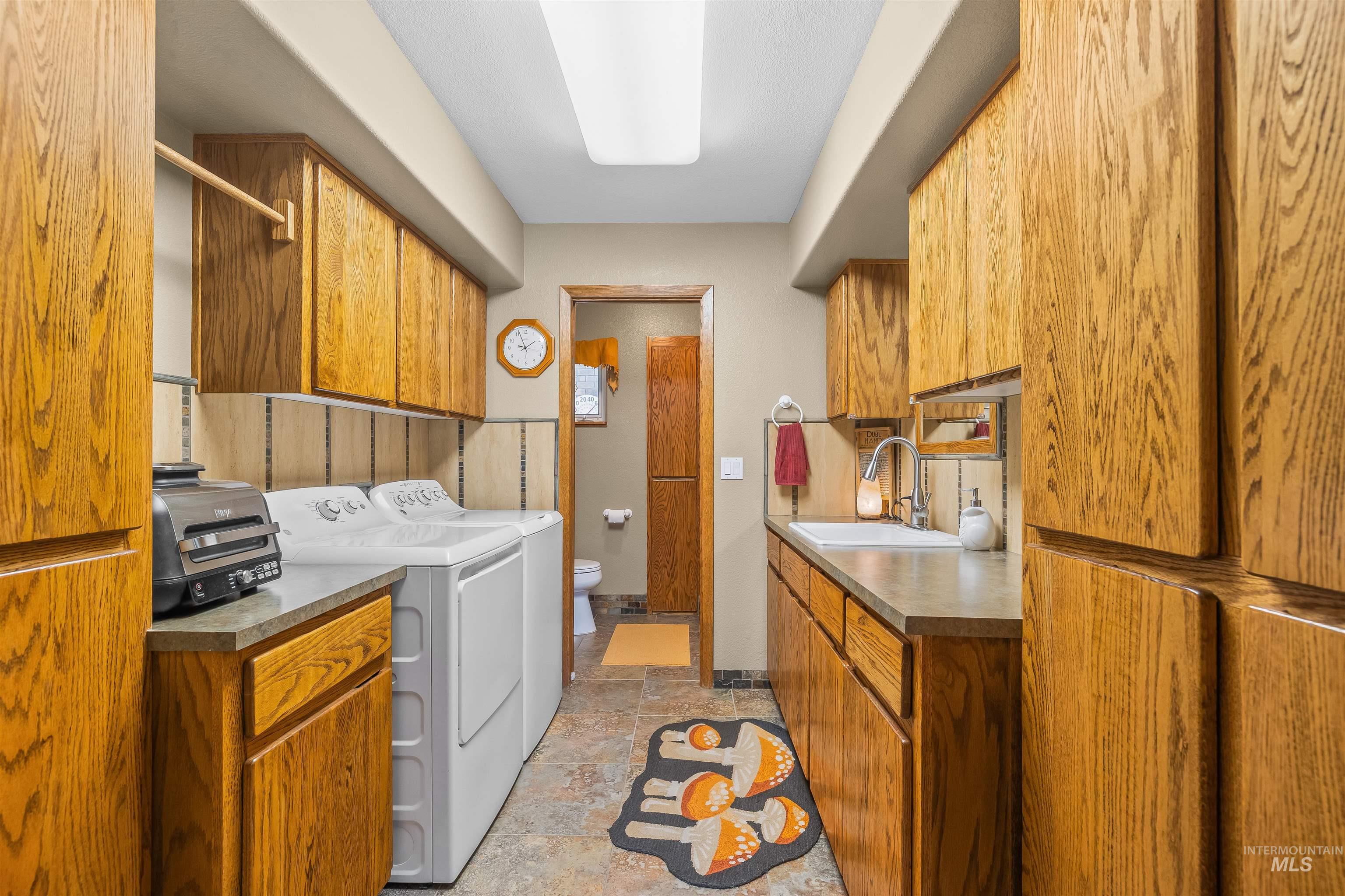 11056 Snake River Road Asotin, WA 99402 - Photo 19 of 50 Laundry area with washing machine and clothes dryer, light stone finish flooring, and cabinet space