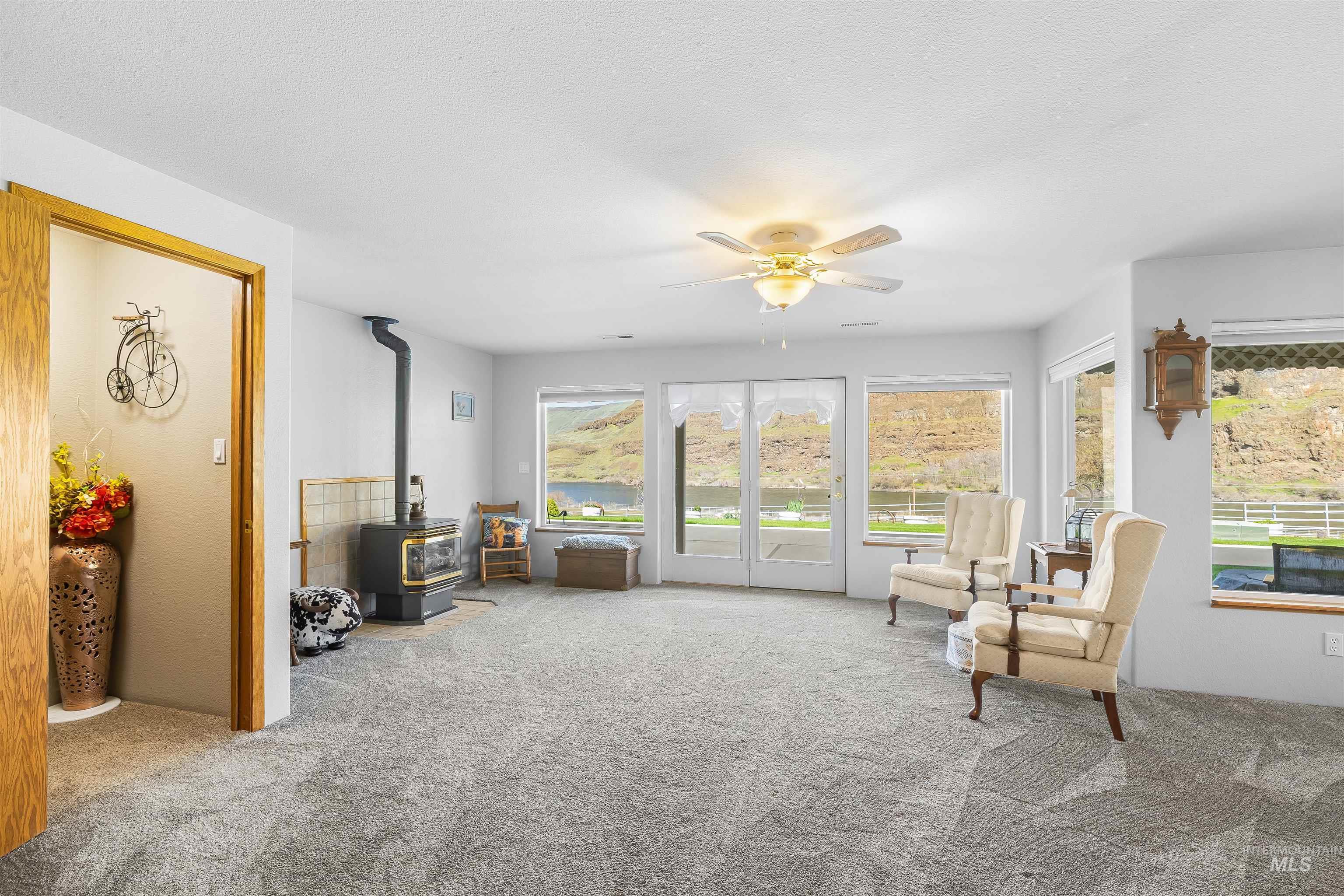 11056 Snake River Road Asotin, WA 99402 - Photo 25 of 50 Sitting room featuring a wood stove, light carpet, and ceiling fan