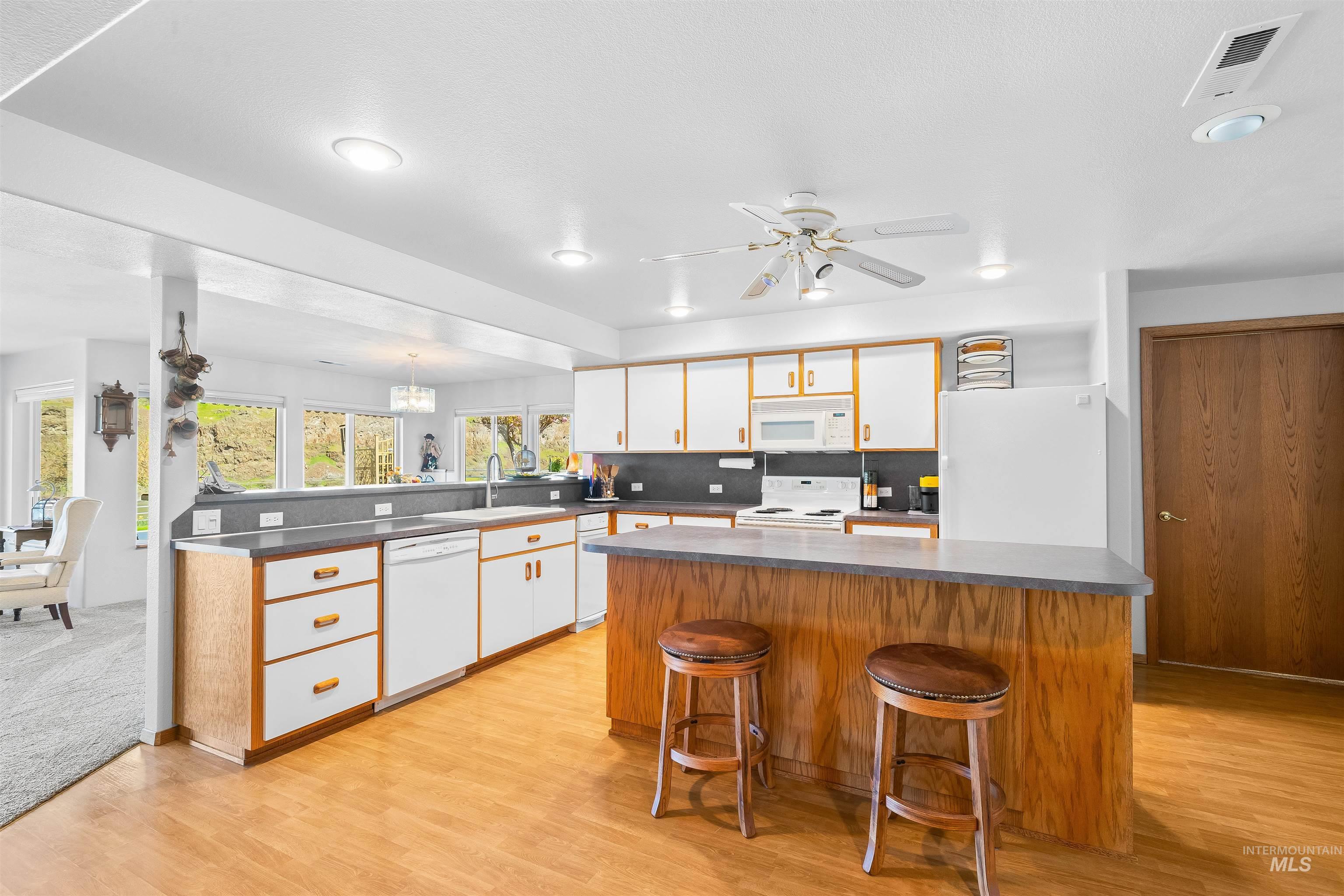 11056 Snake River Road Asotin, WA 99402 - Photo 27 of 50 Kitchen with dark countertops, a kitchen island, a breakfast bar area, dual tone cabinetry, and light wood-type flooring