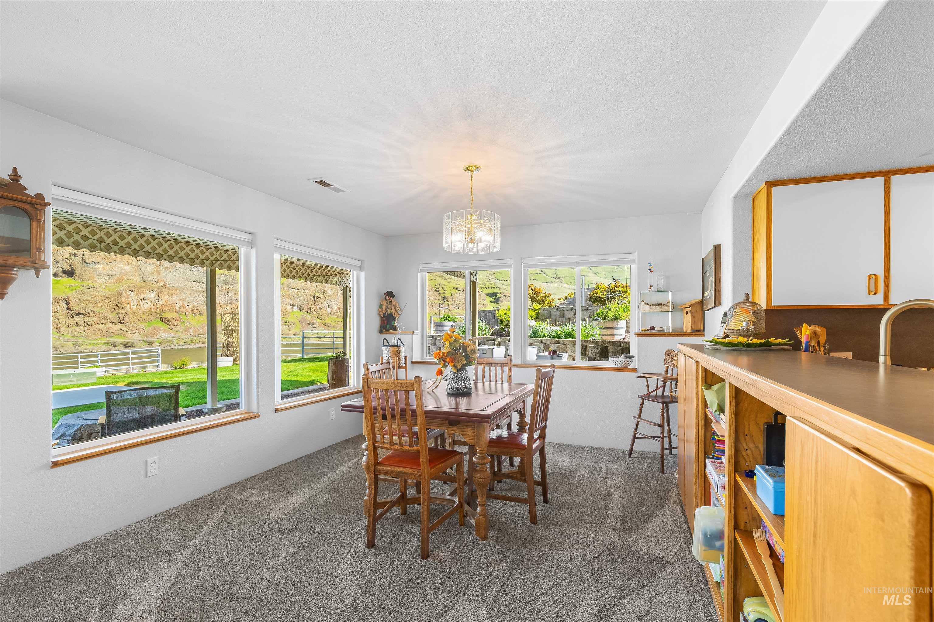 11056 Snake River Road Asotin, WA 99402 - Photo 28 of 50 Dining room with dark colored carpet and a chandelier