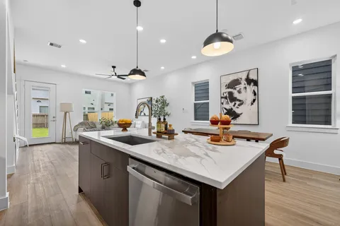 a kitchen with stainless steel appliances kitchen island granite countertop a stove a sink a refrigerator and a dining table with wooden floor