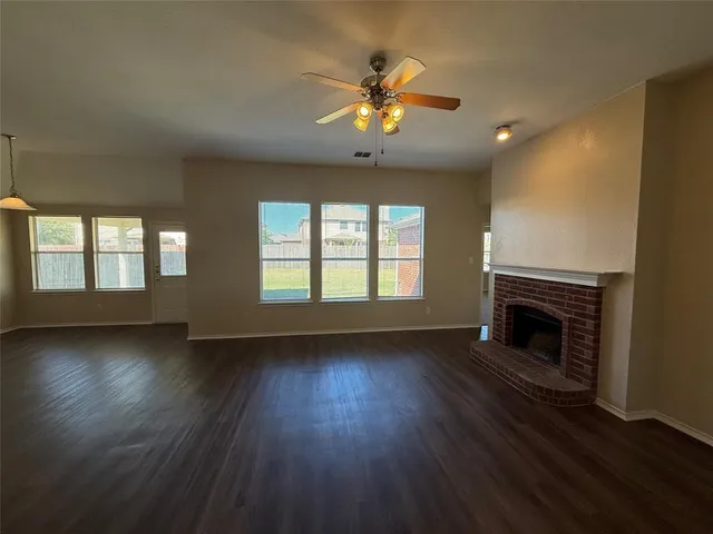 a view of an empty room with wooden floor fireplace and a window