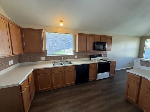 a kitchen with stainless steel appliances granite countertop a sink dishwasher stove and microwave with wooden floor