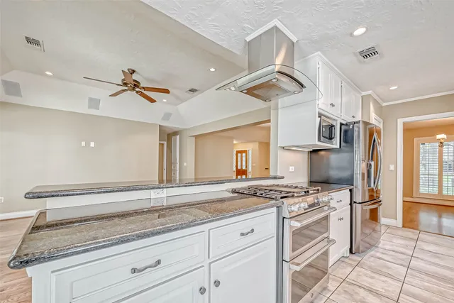 a large white kitchen with granite countertop a sink window and cabinets