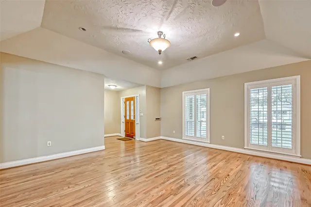 a view of an empty room with window and wooden floor