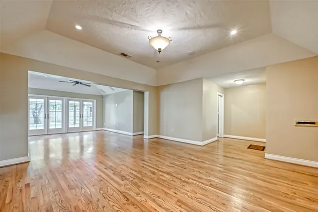 a view of an empty room with a window and wooden floor