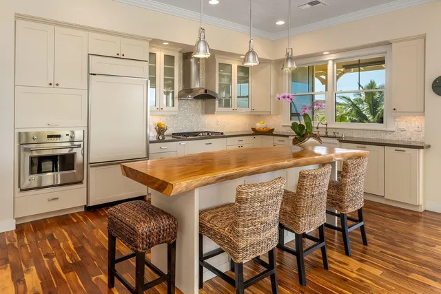 a view of a kitchen with kitchen island a counter top space and stainless steel appliances wooden floor