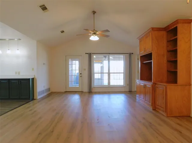 a view of an empty room with wooden floor and a window
