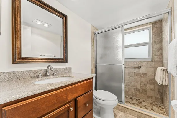 a bathroom with a granite countertop sink toilet and shower
