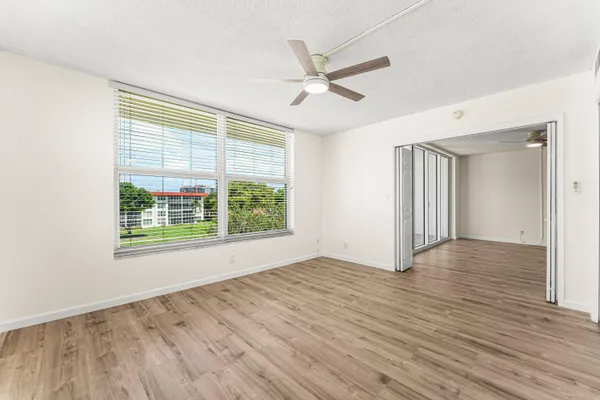 a view of an empty room with wooden floor and a window