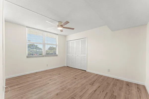 an empty room with wooden floor chandelier fan and windows