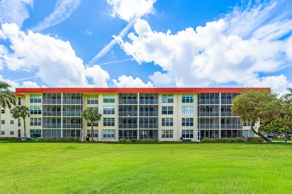 a view of a building with a big yard and large trees