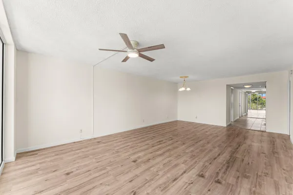 an empty room with wooden floor and a ceiling fan