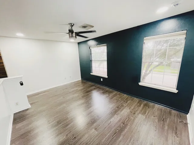 a view of an empty room with wooden floor and a window