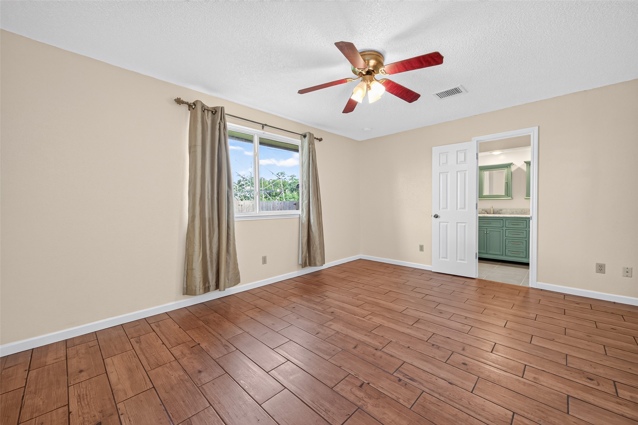 17531 Crestline Road Humble, TX 77396 - Photo 26 of 41 This spacious primary bedroom features elegant wood-look flooring, abundant natural light, and a convenient en-suite bathroom, offering a perfect blend of comfort and style.
