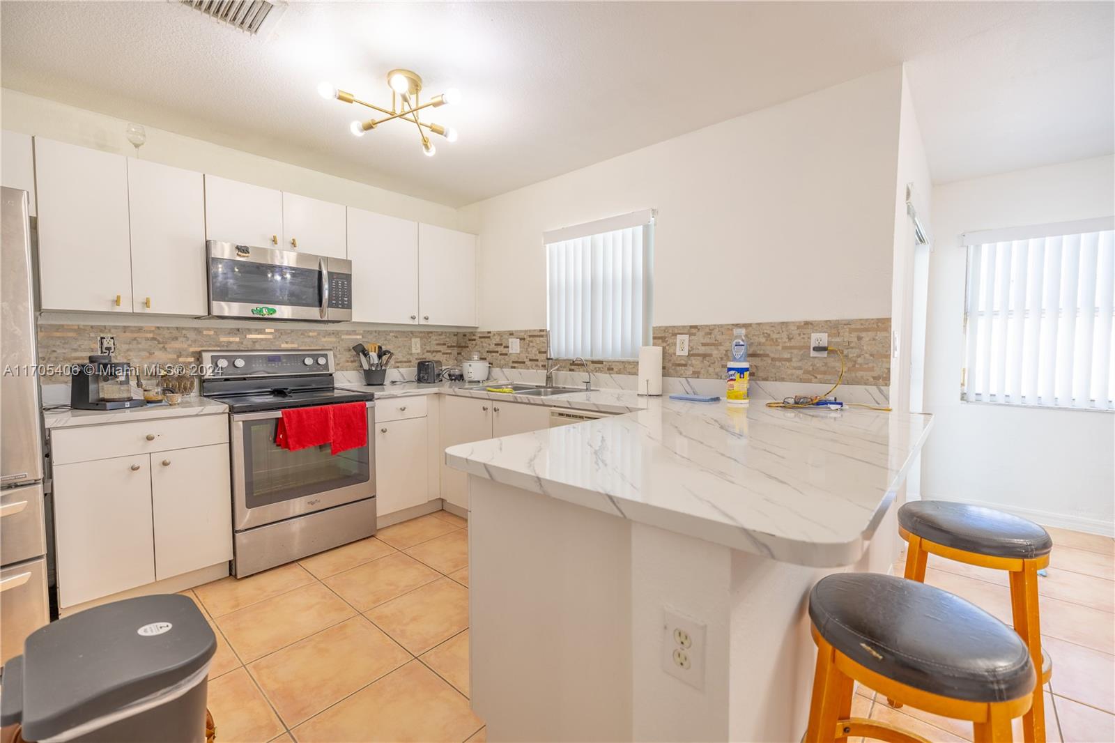 24622 Southwest 112th Court Homestead, FL 33032 - Photo 7 of 22 a kitchen with stainless steel appliances kitchen island wooden cabinets a stove a sink and a refrigerator