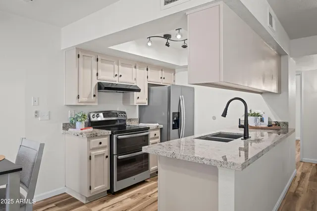a kitchen with granite countertop a sink stainless steel appliances and cabinets