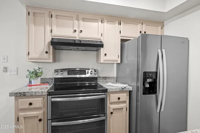 a kitchen with granite countertop a refrigerator stove and cabinets