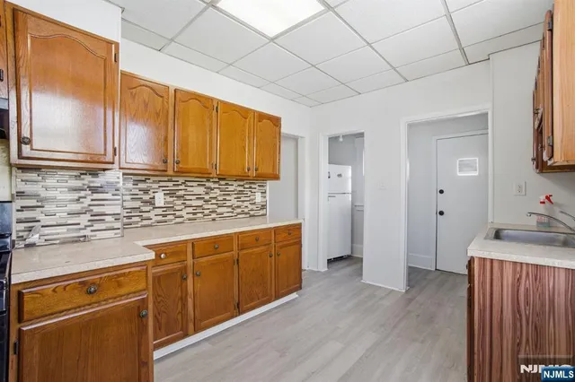a kitchen with stainless steel appliances granite countertop a sink a refrigerator and wooden cabinets